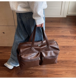 Detail view of large dark brown travel bag with textured leather and dual front zippers
