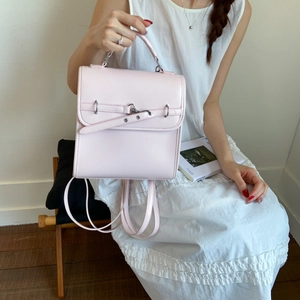 Detail of light pink leather backpack with metal buckles shown in a lifestyle setting