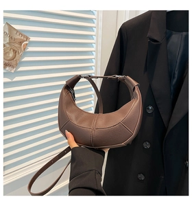 Detail of dark brown crescent bag showing premium leather texture and stitching