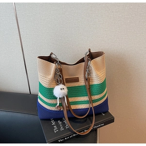 Détail d'un sac cabas en maille rayée avec breloque en peluche sur un livre d'art