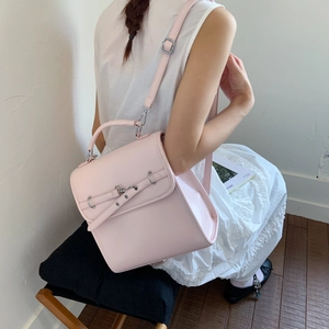Close-up of a pink faux leather backpack featuring a flap closure and silver metal hardware