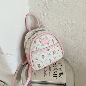 Detailed close-up of a mini white backpack with pink leather trim and bear pattern