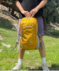 Detail of 40L yellow hiking backpack on grass showing nylon fabric and side mesh pocket