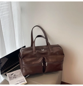 Detail view of large brown faux leather travel bag with dual front zipper pockets
