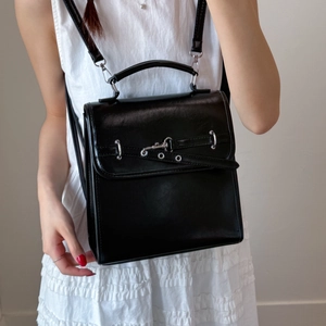Detail of a black vintage leather handbag with silver hardware and decorative straps