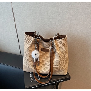 Détail du sac fourre-tout tissé avec anses en cuir brun et pendentif en peluche