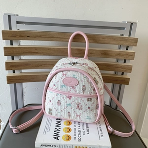 Close-up of quilted mini backpack featuring cute cartoon bear and strawberry patterns