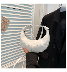 Detail of white lychee leather dumpling bag with stitching and adjustable shoulder strap