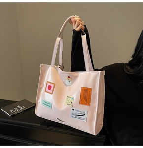 Close-up of a pink tote bag with stylish embroidery patches and glossy leather texture