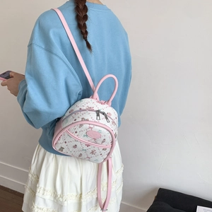 Detailed back view of a mini pink and white cartoon bear backpack on a model