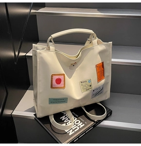 Detail of off-white tote bag with cartoon patches and embroidery for casual look