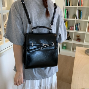 Detail of black glossy leather backpack featuring silver hardware and adjustable straps