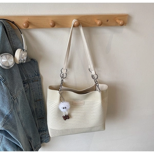 Détail du sac en tricot crème avec peluche et chaîne en métal sur crochet en bois