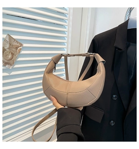 Detail of beige crescent moon bag showing premium lychee texture leather and strap