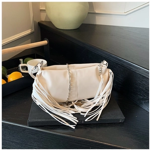 Detail shot of beige pleated handbag with fringe tassels and metallic chain strap