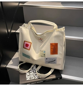 Detail of cream multi-way tote bag with colorful patches on a minimalist urban background
