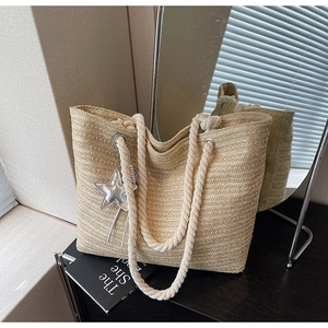 Detail of woven straw tote bag with cotton rope handles and a silver star charm