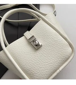 Close-up of white lychee pattern leather texture with metal twist-lock and fine stitching