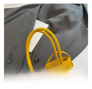 Detail showing high-quality leather texture and silk ribbon on the yellow mini handbag