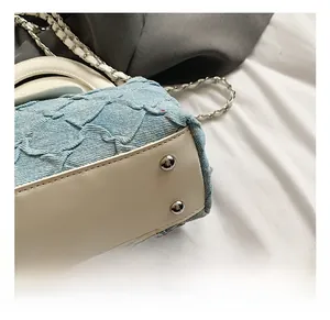 Nahaufnahme der Patchwork-Tasche aus hellblauem Denim und Leder mit silbernen Nieten