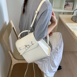 Lifestyle shot of a white PU leather backpack with metallic buckle and adjustable straps