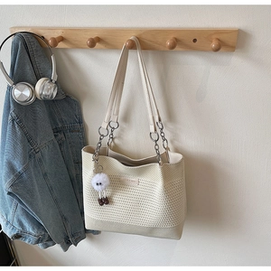 Détail du sac cabas tissé crème avec chaîne argentée et breloque peluche monstre