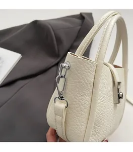 Detail of silver twist lock and lychee pattern leather on white bucket handbag