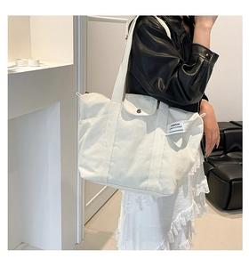 Detail view of large cream canvas tote bag with side pocket and magnetic flap closure