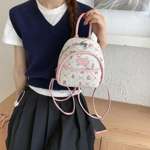 Detailed close-up of white mini backpack featuring cute cartoon bear and strawberry patterns