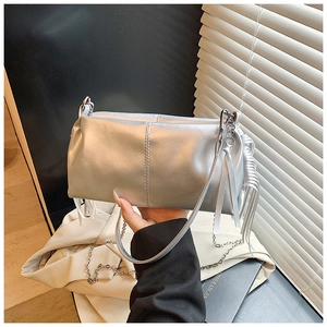 Detail of silver metallic handbag featuring side tassels and chain strap in a city setting