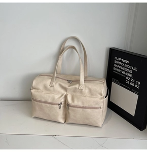 Detailed close-up of cream PU leather tote bag with functional zippered front pockets