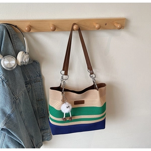 Détail du cabas tricoté tricolore avec logo en cuir et breloque peluche sur crochet en bois
