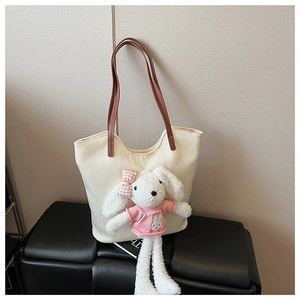 Dettaglio di una borsa tote in tessuto beige con un simpatico coniglio di peluche e fiocco
