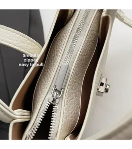 Detail of smooth silver zipper and lychee pattern leather on off-white bucket bag