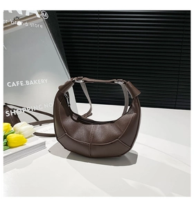Close-up of deep brown crescent bag showing high-quality lychee grain leather and stitching