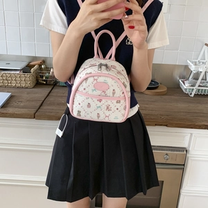 Detailed view of woven mini backpack with pink leather trim and cute cartoon prints