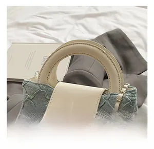 Detail der hellblauen Handtasche aus Strukturstoff mit weißem Ledergriff und Silberschloss