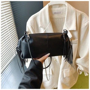 Detail of black pleated baguette bag with long side tassels and fine leather shoulder strap