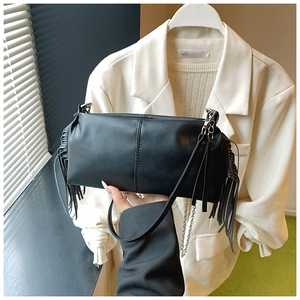 Detail of black baguette bag with stylish side tassels and metallic chain accessory