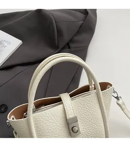 Detailed macro of cream bucket bag showing lychee grain leather and silver twist lock