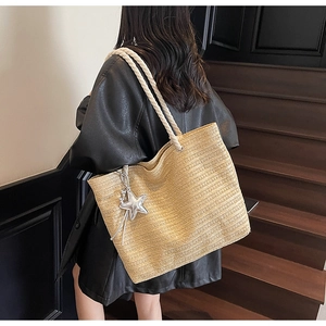 Detailed view of beige woven tote bag with white rope handles and silver star charm