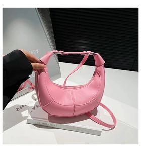 Detail of pink crescent bag with lychee texture and adjustable strap on book prop
