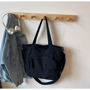 Detail of black nylon tote with detachable coin purse and adjustable strap on a wall hook