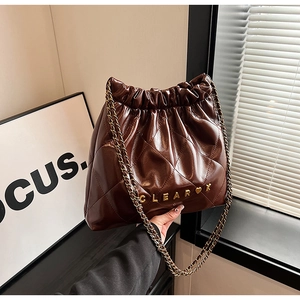 Detailed macro view of brown quilted PU leather bucket bag with chain strap and drawstring