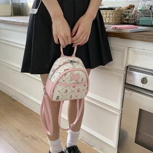 Close-up of mini backpack with cute bear print and pink leather trim being held by hand