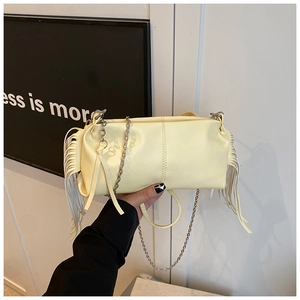 Detail of pale yellow pleated handbag featuring side tassels and a silver chain strap