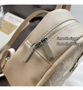 Vue rapprochée d'une fermeture éclair argentée sur un sac à dos beige aux coutures blanches