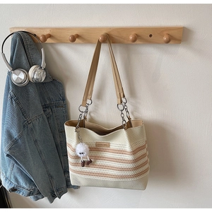Détail du sac fourre-tout en maille rayée avec bandoulière en cuir et pompon en peluche