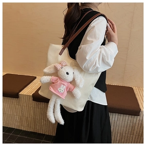 Dettaglio borsa tote in tessuto crema con spalline in pelle e ciondolo a forma di coniglio