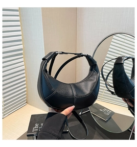 Close-up of black lychee grain leather handbag with geometric stitching and metal clasp